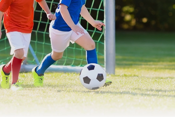 ゴール前でサッカーボールを追う子どもたち